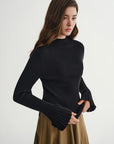 Woman wearing a black ribbed sweater and beige skirt on a white background