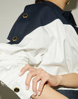 Close-up of a person wearing a navy and white jacket with gold buttons.