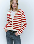 Woman wearing a red and white striped cardigan with a plain background