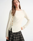 Woman wearing a cream-colored cardigan with button details on a white background