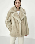Beige faux fur coat on a hanger against a white background