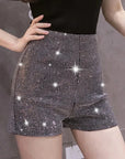 Black shorts with sparkling rhinestones worn by a person on a neutral background