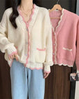 Woman wearing a cream cardigan with pink trim, standing next to a pink cardigan on a hanger.