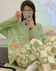 Person wearing a green outfit with cartoon designs, sitting on a bed.