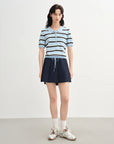 Woman wearing a striped shirt and navy skirt on a white background