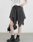 Person wearing a plaid skirt and black boots on a plain background