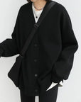 Person wearing a black cardigan over a white shirt on a white background