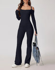 Woman wearing a black jumpsuit holding a denim bag on a white background