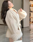 Woman wearing a beige coat with fur trim in an indoor setting