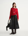 Woman wearing a red sweater and black skirt with a white background